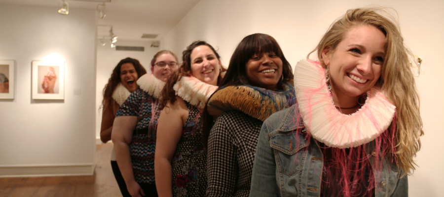 5 women laughing in a line inside a museum 